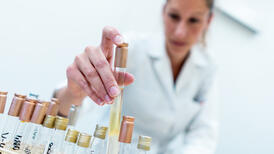 Focus sur la main d'une laborantine tenant un tube de laboratoire