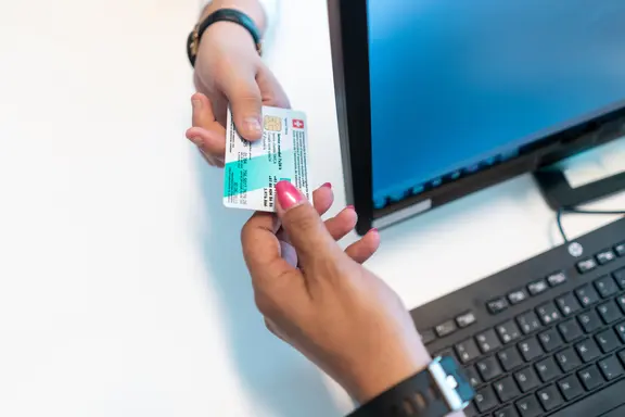 Photo d'une formalité d'admission: gros plan sur une main qui tient une carte d'assurance 