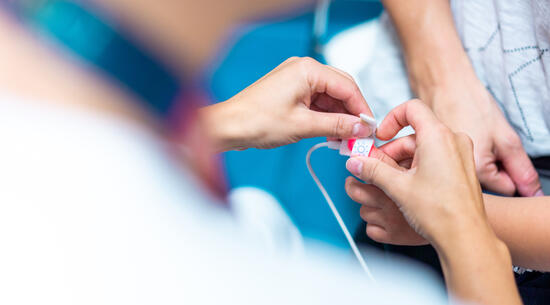 Gros plan sur les mains d'un médecin en train de poser un sparadrap sur le doigt d'un enfant. 
